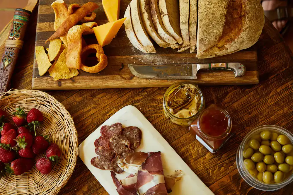 A lavish spread of deli meats, fresh bread, and antipasti on a rustic wooden board